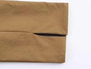 Detailed macro view of khaki trench coat sleeve with vintage plaid lining and stitching