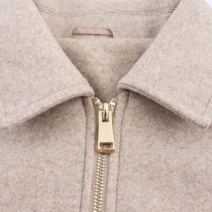 Close-up of soft beige wool blend fabric with premium gold metal zipper detail
