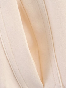 Detail of premium beige button jacket showing high-quality stitching and textured fabric