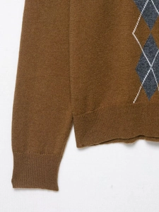 Detailed close-up of argyle knit pattern and ribbed cuff on brown polo sweater
