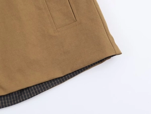 Close-up of khaki trench coat detail showing twill fabric texture and plaid lining