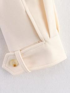 Close-up of cream textured jacket cuff featuring marble resin button and decorative strap