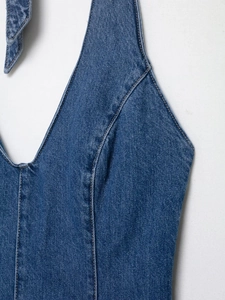 Detailed close-up of blue wash denim halter top with yellow stitching and deep V-neckline