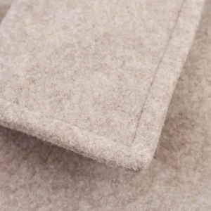 Detailed close-up of soft beige wool blend fabric with high-quality edge stitching craftsmanship