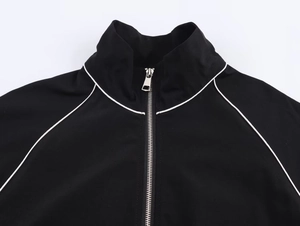 Detail of a black nylon bomber jacket with a silver zipper and white contrast piping