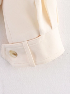 Detail of cream jacket cuff featuring amber button and fine double stitching detail