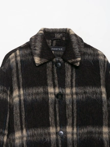 Close-up of black and beige plaid wool coat featuring a classic collar and dark buttons