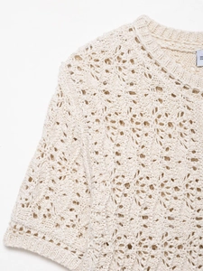 Détail macro du pull en maille crochetée blanche montrant l'encolure et la texture du tissu