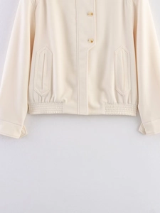 Detail of cream cropped jacket with amber buttons and hexagonal pocket flaps