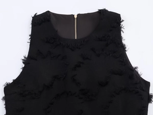 Close-up of black sleeveless top featuring fringe texture and golden metal back zipper
