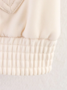 Macro shot of cream jacket hem with twill texture and elastic ribbed cuff detailing