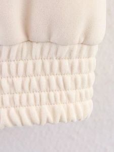Close-up of cream white fuzzy jacket sleeve with triple-stitched elastic ribbed cuff