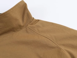 Detail of camel brown jacket showing the stand collar and raglan sleeve stitching