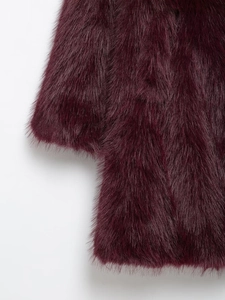 Gros plan macro montrant la texture dense et brillante du manteau en fausse fourrure bordeaux