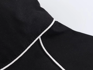 Macro view of black nylon puff jacket with contrast white piping and seam details