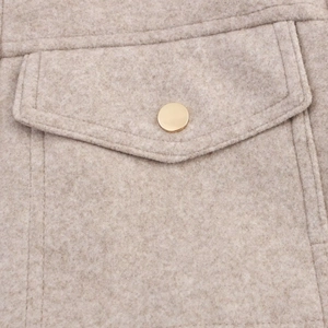 Detail of light beige wool jacket showing a pocket flap with gold metal button fastener