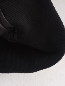 Nahaufnahme der schwarzen Rippstrickbündchen und Kragentextur einer Fliegerjacke