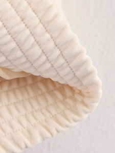 Detailed close-up of cream-colored quilted jacket fabric with horizontal striped texture