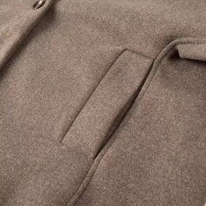 Detail view of brown wool blend fabric and pocket stitching on a loose v-neck coat