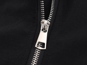 Detail of high-quality silver metal zipper on a black nylon bomber jacket with neat stitching
