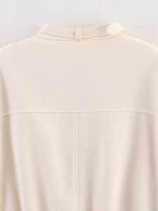 Close-up of cream textured jacket featuring a stand collar with tab and fine stitching
