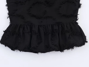 Detail of black top featuring fringed ring texture and elegant peplum hemline