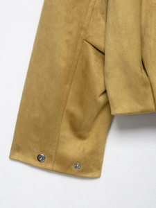 Vue détaillée du revers de la veste en daim moutarde avec boutons-pression et coutures fines