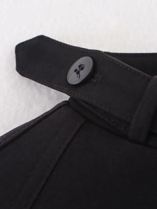 Detail view of black twill jacket featuring a round button and adjustable side tab design