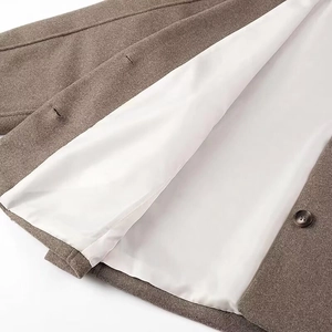 Detailed shot of brown wool coat fabric texture with button and white silky lining