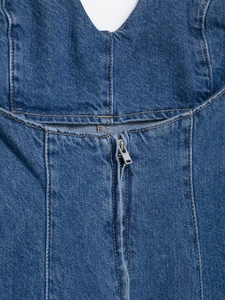 Detailed close-up of blue denim dress featuring a V-neckline and metal YKK zipper closure