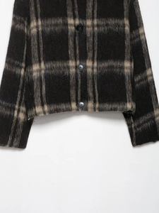 Close-up of thick plaid wool jacket with plush texture and polished black buttons