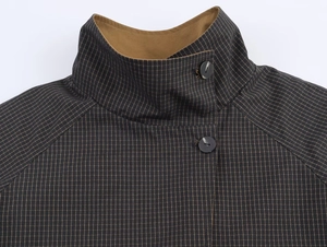 Detail view of the standing collar and dark plaid fabric on this reversible short jacket