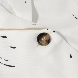 Close-up of marble texture button and black graffiti print on white blazer fabric
