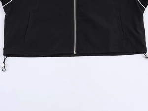 Detail of black nylon jacket hem featuring adjustable silver drawcord and metal zipper