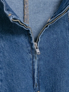 Detailed close-up of dark denim fabric with high-quality YKK metal zipper and yellow stitching