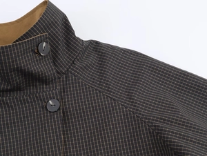 Detail of dark blue checkered jacket featuring a stand collar and round black buttons
