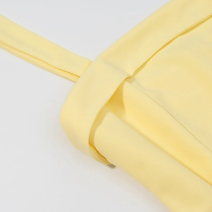 Détail de couture sur tissu en mousseline jaune pâle d'une robe longue à col licou