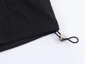 Detail of nylon puffer jacket hem featuring elastic drawstring and silver metal toggle