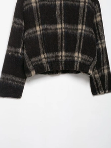 Close-up of fuzzy plaid jacket fabric with black, beige and blue checkered patterns