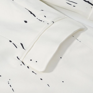 Close-up of the stitching on a cream blazer with black ink graffiti print texture