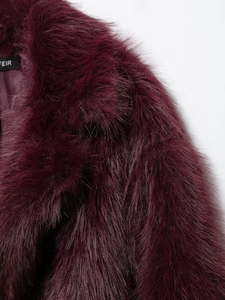 Gros plan sur la texture en fausse fourrure bordeaux et la couture du col