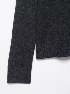 Detailed close-up of dark charcoal gray knit fabric with soft texture and ribbed cuffs