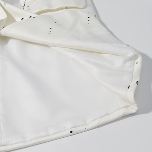 Detailed close-up of white blazer showing inner lining and black ink dot print patterns
