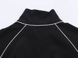 Close-up of black nylon bomber jacket featuring white piping details on collar and sleeves
