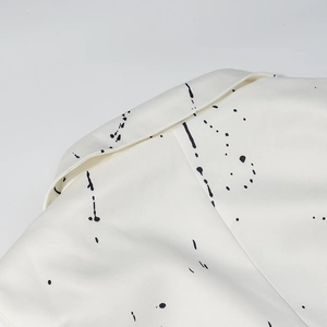 Detailed macro view of white lapel collar featuring artistic black ink splatter patterns