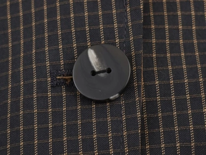 Macro detail of dark checkered jacket fabric with a marble textured button closure