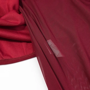 Gros plan détaillé sur la texture du tissu en maille rouge foncé et les coutures de la robe