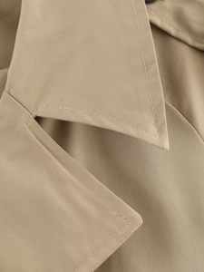 Close-up of double-stitched lapel and khaki twill fabric on women's cropped trench coat