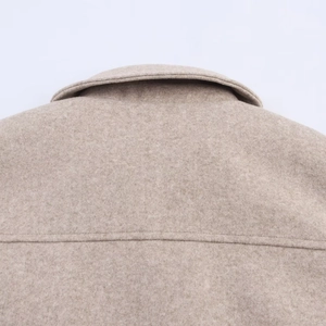 Close-up of wool texture and precise stitching on the collar of a beige jacket