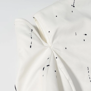 Close-up of white V-neck blazer with black graffiti print and tailored pleat details